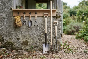 Ordentlich aufgereihtes Gartenwerkzeug wie Spaten, Harke und Handschuhe