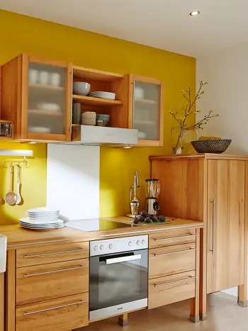 Küche mit Möbeln aus nachhaltigem Naturholz vor gelber Wand
